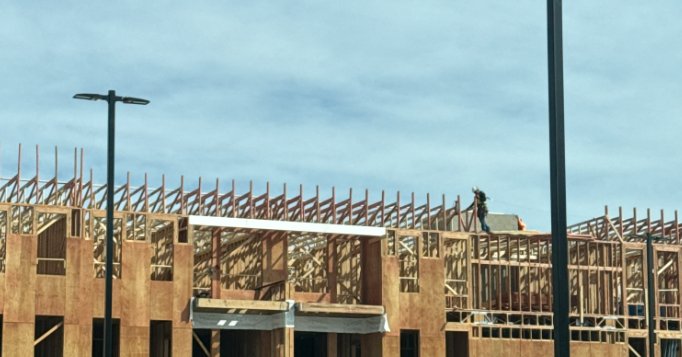 Wood Framers crew framing the roof line of a multifamily building under a blue Colorado sky
